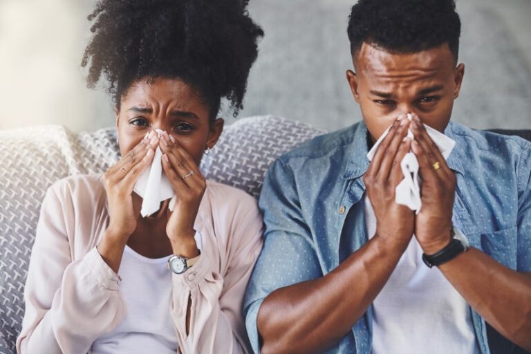 Sick Couple Sneezing Into Tissues